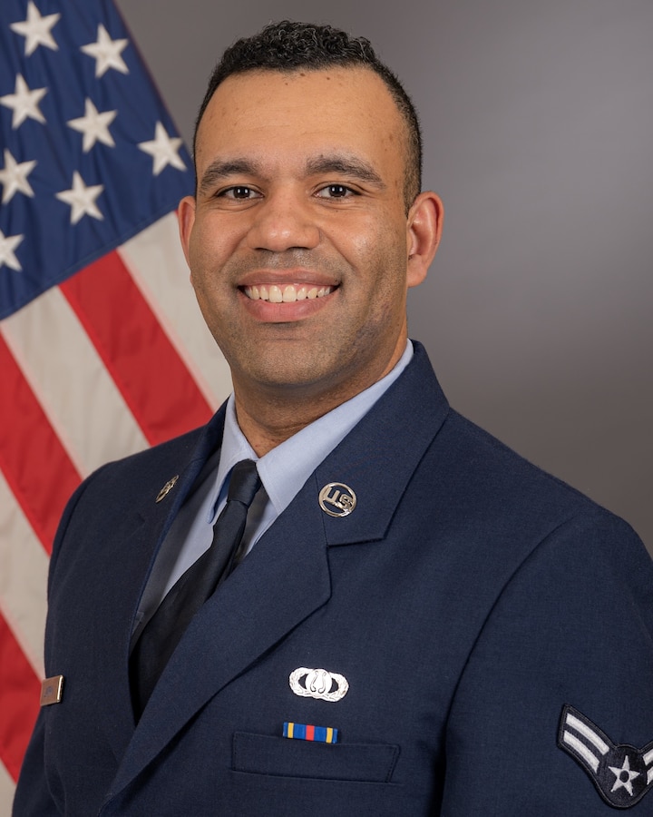 Official bio photo of A1C Christian Lampkin in front of the American flag. He is wearing the blue service dress uniform.