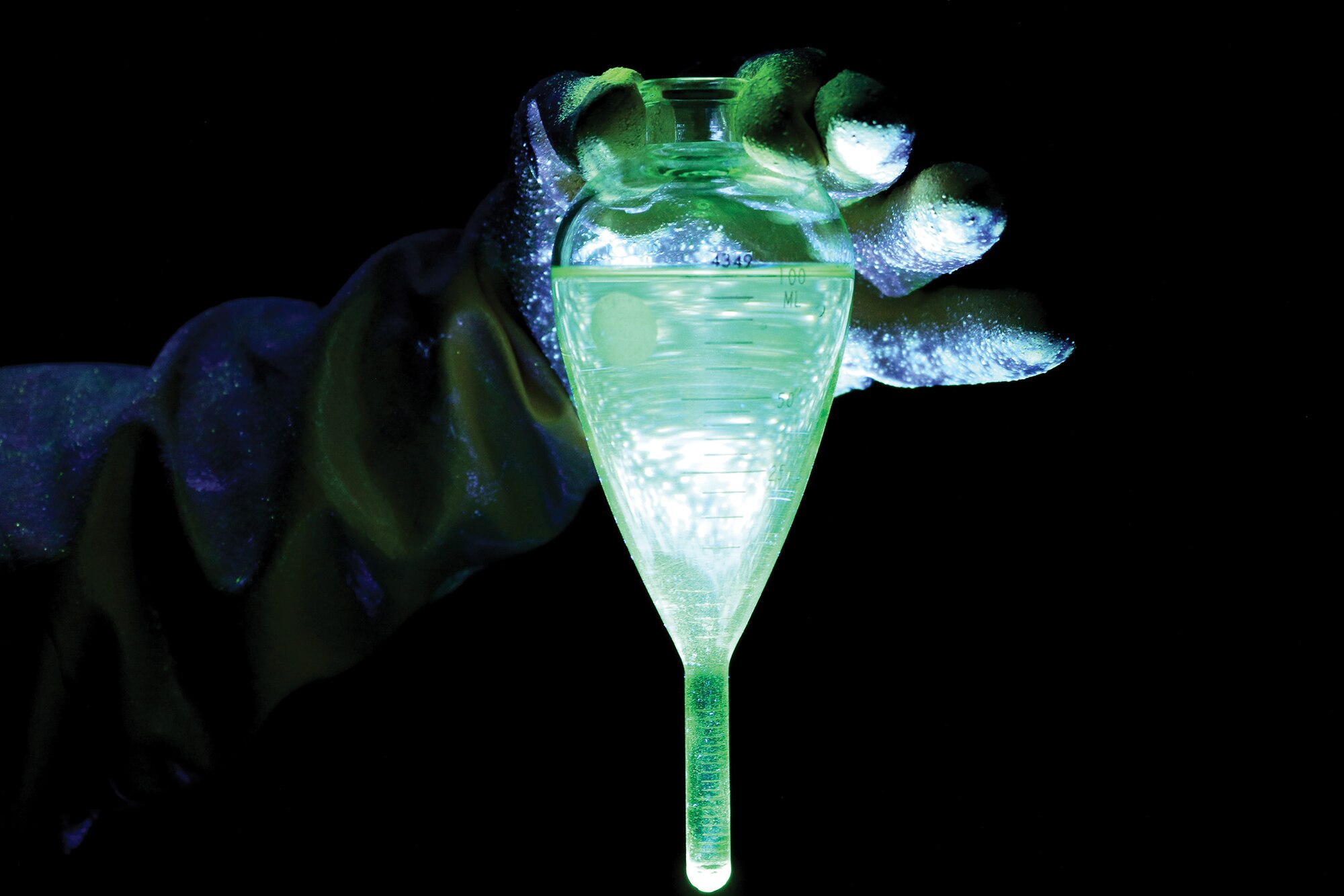 Senior Airman Stephanie Gillispie, 445th Maintenance Squadron non-destructive inspector, holds the fluorescent oil used in a magnetic particle bath under a ultraviolet light at Wright-Patterson Air Force Base, Ohio, Feb. 4, 2024.