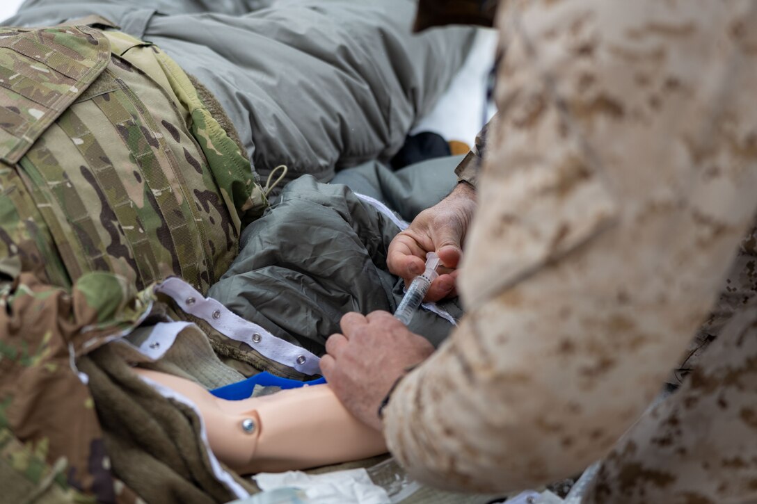 U.S. Navy HMC Peter Harding, a hospital corpsman with 1st Marine Division, I Marine Expeditionary Force, demonstrates Tactical Combat Casualty Care (TCCC) under arctic conditions to a joint-service delegation during Distinguished Visitor’s (DV) Day as part of exercise Arctic Edge 2024 (AE24) at Joint Base Elmendorf-Richardson, Alaska, March 4, 2024. The delegation visited and toured Camp Mad Bull, a site conducting several medical experiments in an arctic environment utilizing freeze dried plasma, portable oxygen generators, hypothermia prevention devices, core temperature monitors and more. AE24 DV Day fostered dynamic discussions among military, government, and academic leaders on arctic homeland defense, later featuring site visits, demonstrations, and presentations. Arctic Edge 2024 is a U.S. Northern Command-led homeland defense exercise demonstrating the U.S. military’s capabilities in extreme cold weather, joint force readiness, and U.S. military commitment to mutual strategic security interests in the arctic region. (U.S. Marine Corps photo by Lance Cpl. Madisyn Paschal)