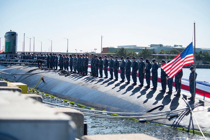 Sailors stand atop a submarine.