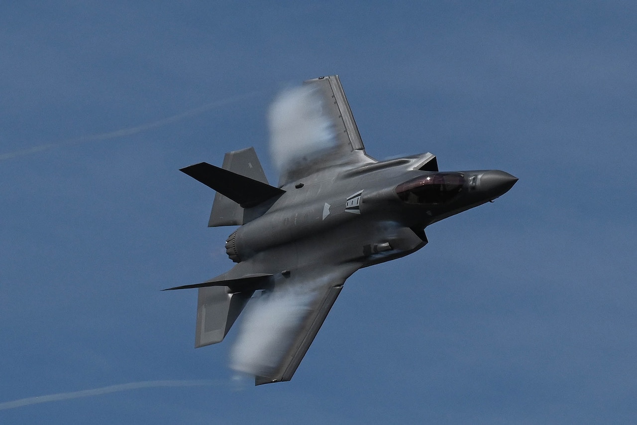 A military fighter aircraft flies against a blue sky.