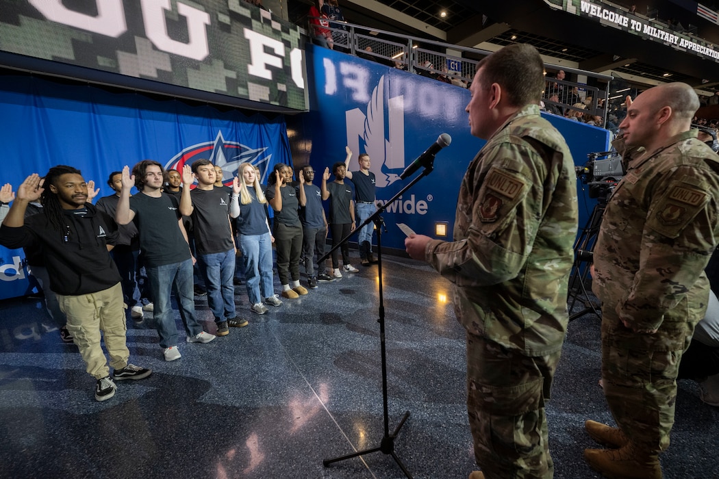 A man in military uniform administers oath to people 16 people.