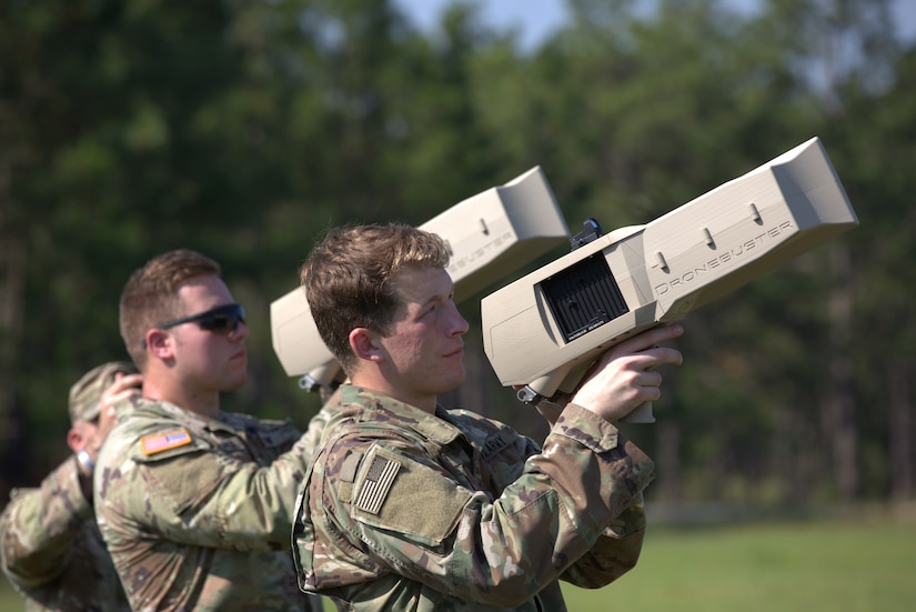 Soldiers in uniform point devices into the air.