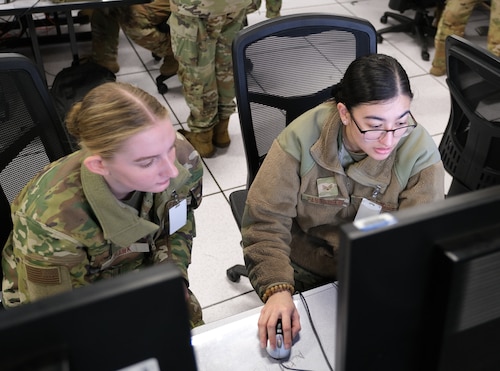 uniformed U.S. Air Force Airmen work at computers