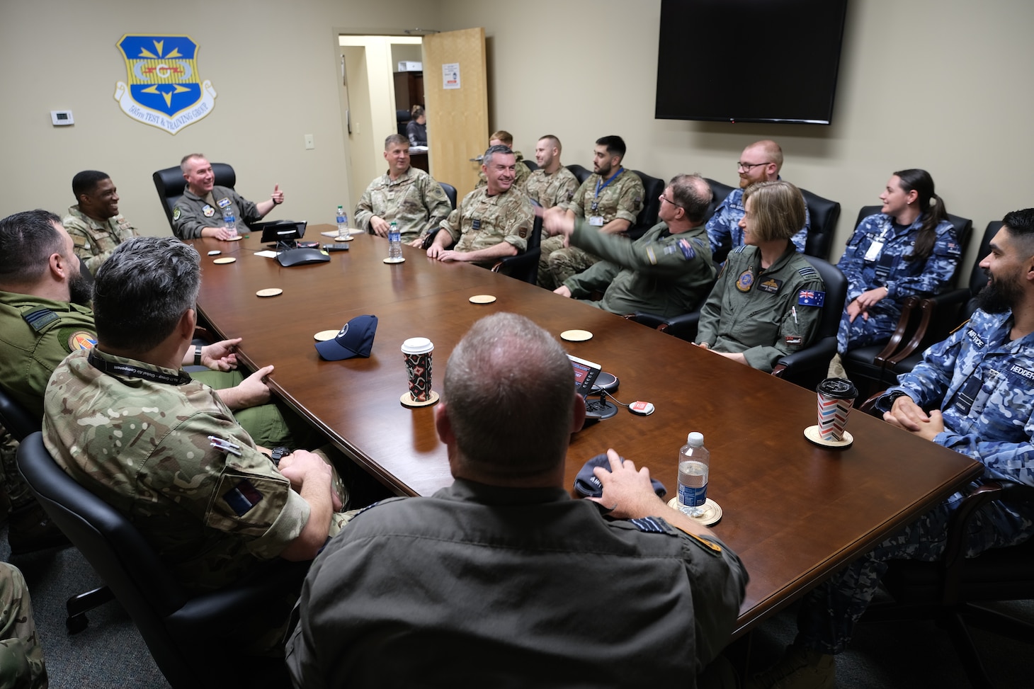 photo of uniformed U.S., U.K. and Australian Air Force members sitting at a conference table talking