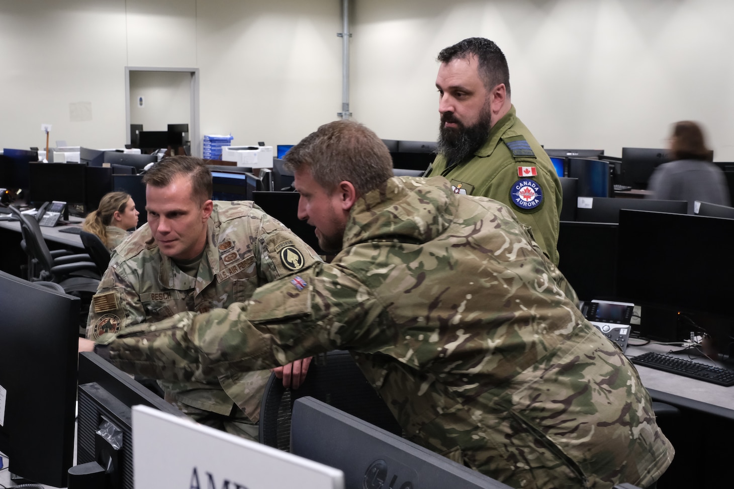 uniformed U.S. U.K, and Canadian military members working at computers