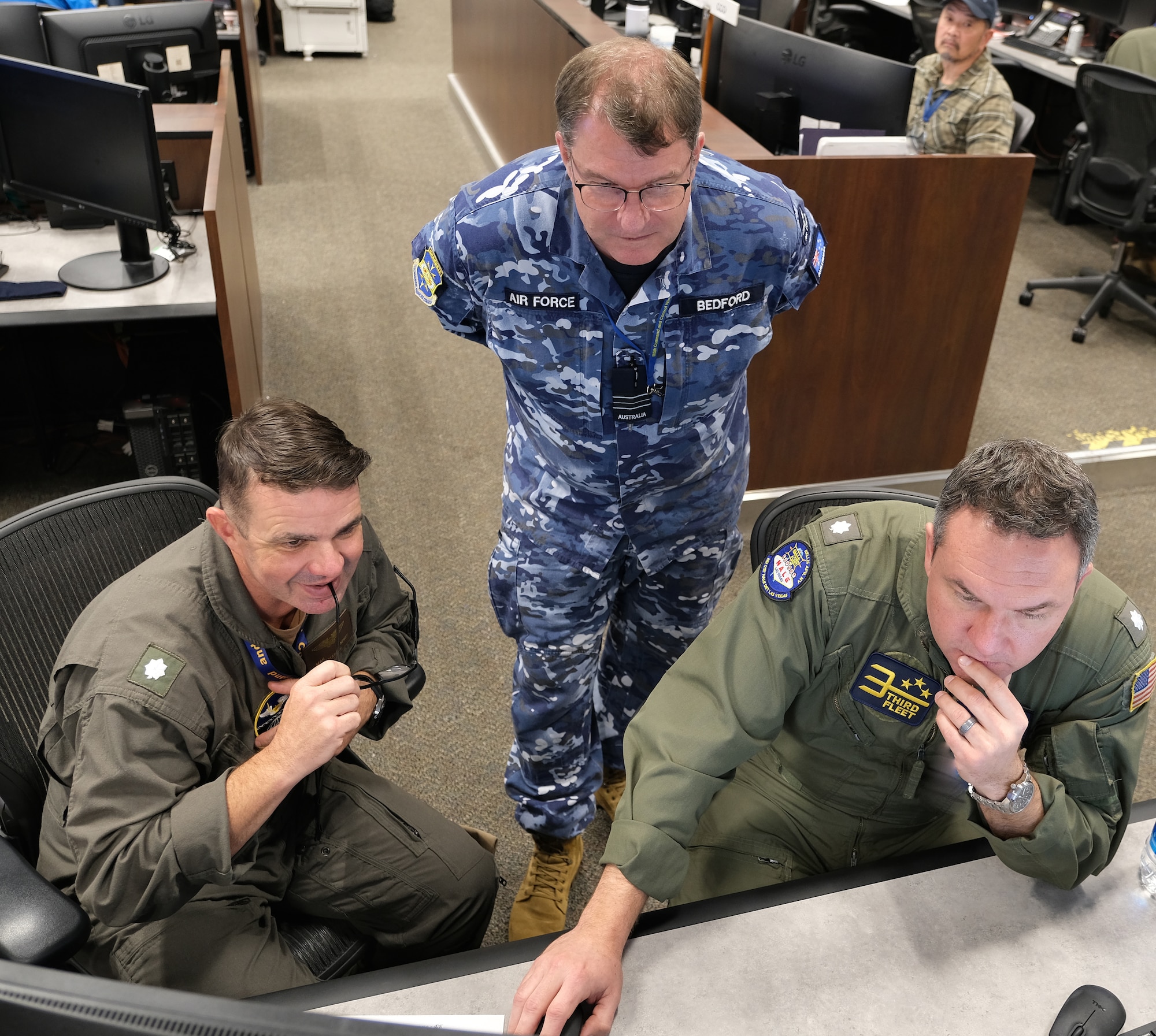 uniformed military members working at computers.