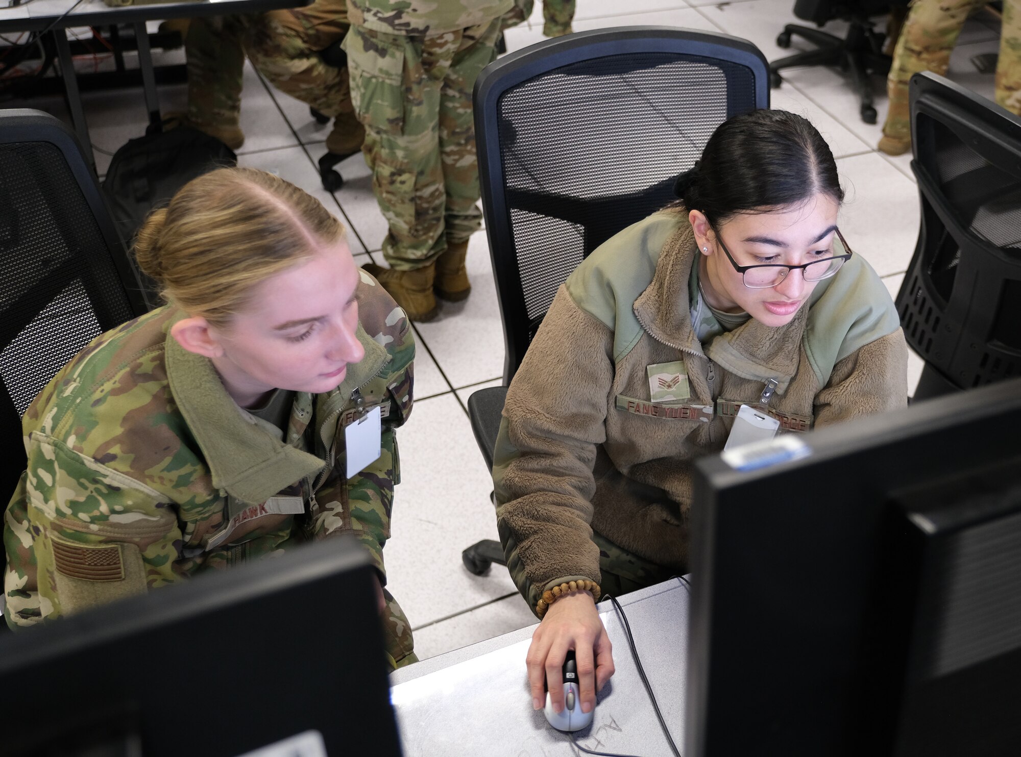 uniformed U.S. Air Force Airmen work at computers
