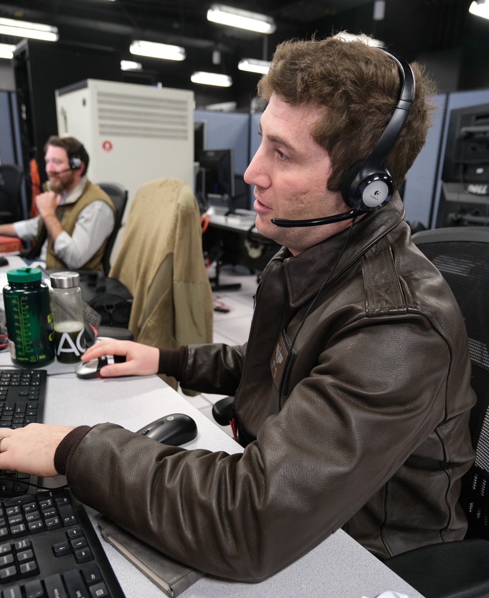 uniformed U.S. Air Force Airman wearing headset works at a computer