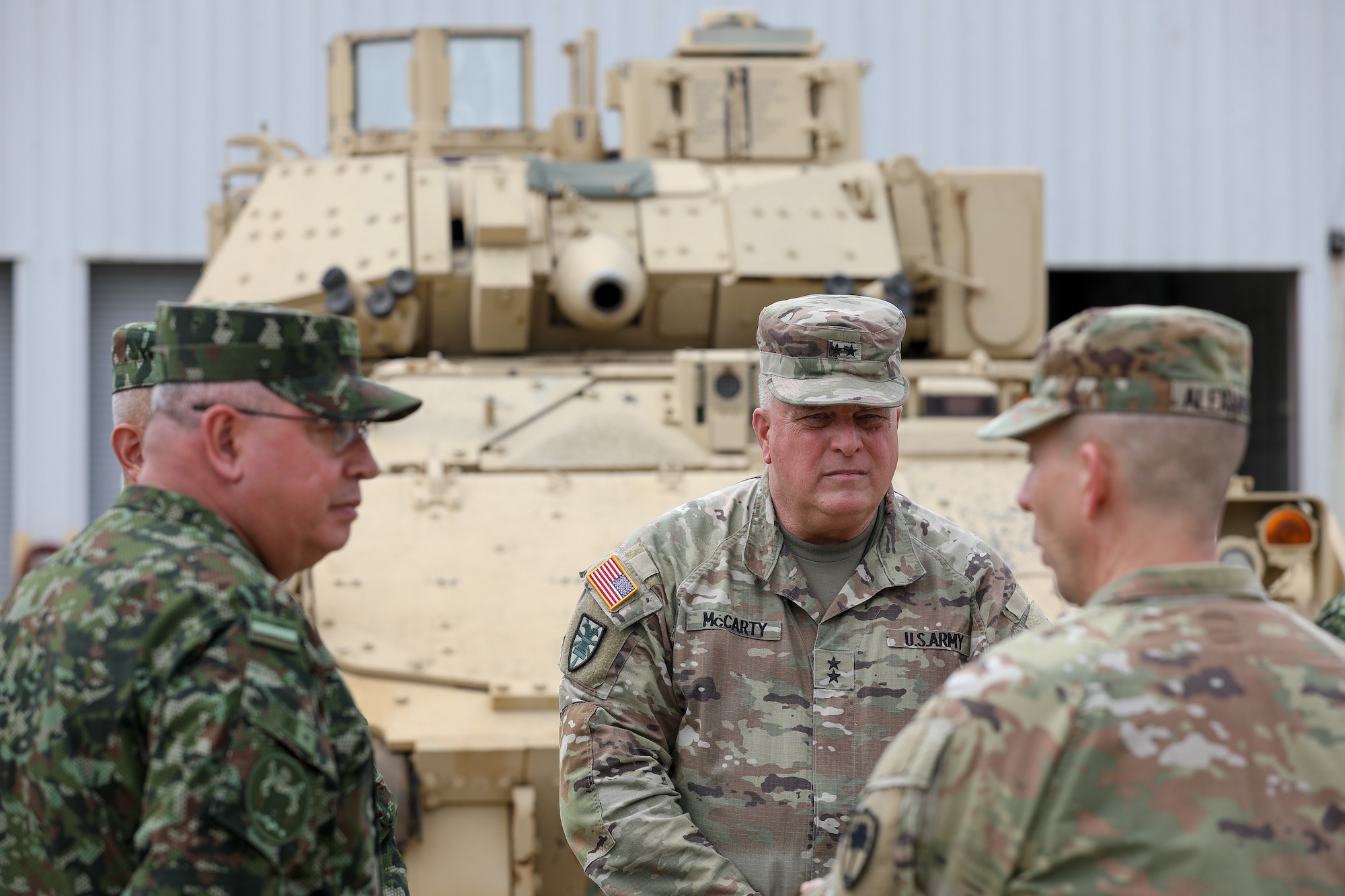 Airmen talk to each other in front of a tank