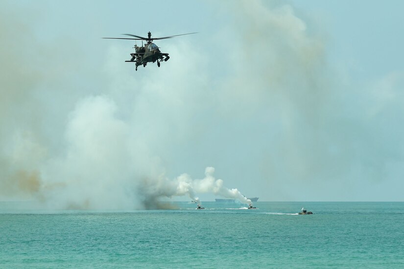 A U.S. Army AH-64 Apache helicopter flies over water during an amphibious assault during exercise Cobra Gold at Hat Yao Beach, Cobra Gold, Rayong Province, Thailand, March 1, 2024. Exercise Cobra Gold is the largest joint exercise in mainland Asia and a concrete example of the strong alliance and strategic relationship between Thailand and the United States. This year is the 43rd iteration of the multilateral exercise and occurs between Feb. 27 to March 8, 2024. (U.S. Marine Corps photo by Cpl. Emily Weiss)