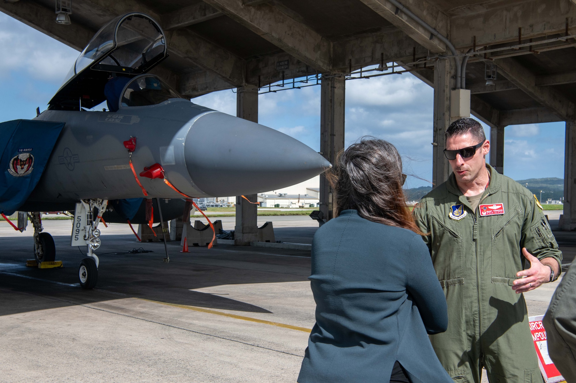 Two people talk in front of an F-15.