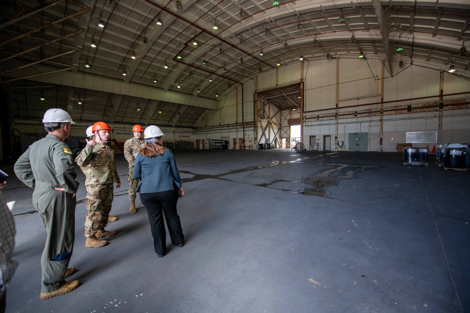 A group of people talk in a hangar.