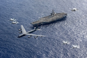 A U.S. Air Force B-52 Stratofortress, attached to the 5th Bomb Wing, and aircraft attached to Carrier Air Wing (CVW) 11, fly in formation over the Nimitz-class aircraft carrier USS Theodore Roosevelt (CVN 71)