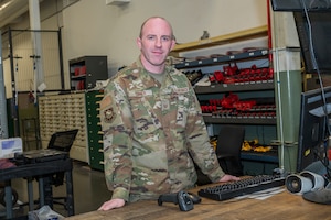 a man stands at a counter with racks of tools behind him