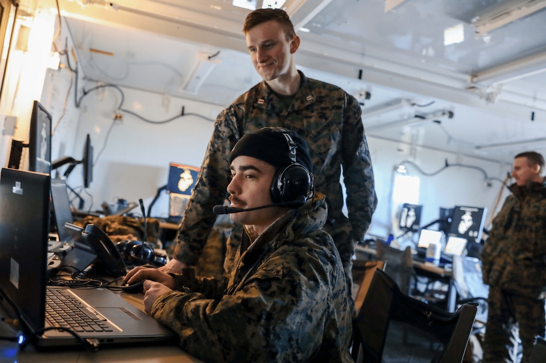 U.S. Marine Corps Capt. Drew Noble, an air defense control officer with Marine Air Control Squadron 24 (MACS-24), Marine Air Control Group 48, 4th Marine Aircraft Wing, Marine Forces Reserve, monitors Gunnery Sgt. Derek Sanford, an air defense controller with MACS-24, as he coordinates fire missions from the Multifunction Air Operations Center (MAOC) in support of Exercise Arctic Edge 2024 at Fort Greely, Alaska, Feb. 19, 2024. The MAOC employs the AN/TPS-80 Ground/Air Task Oriented Radar for air surveillance, delivering expeditionary aviation command and control to the Marine Air-Ground Task Force. Arctic Edge 2024 (AE24) is a U.S. Northern Command-led homeland defense exercise demonstrating the U.S. military’s capabilities in extreme cold weather, joint force readiness, and U.S. military commitment to mutual strategic security interests in the arctic region. Noble is a native of Hingham, Massachusetts. Sanford is a native of Zephyrhills, Florida. (U.S. Marine Corps photo illustration by Lance Cpl. Madisyn Paschal)(Photo was edited for operational security)