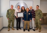 Healthcare Simulation and Bioskills Training Center (HSBTC) staff with the American College of Surgeons (ACS) reaccreditation certificate. From the left, Cmdr. Chris Smith, HSBTC deputy director; Don Delorey, research scientist; Rebecca Kiser, lead nurse educator; Clint Rombaoa, Simulation Center acting manager; Jon Lorenz, Bioskills Center manager; Cmdr. Levi Kitchen, HSBTC director. Members of the HSBTC team not pictured are Cmdr. Tamara Kemp, Surgical director, and Cmdr. Liza Stone, Nursing director.