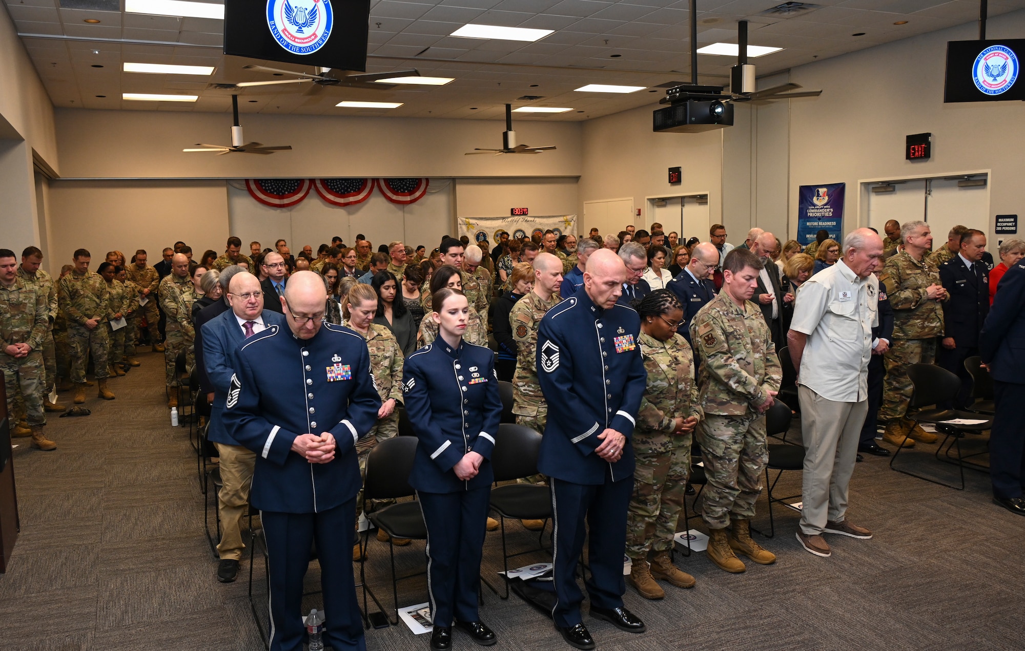 Overhead shot of standing Air Force members attending an indoors ceremony.
