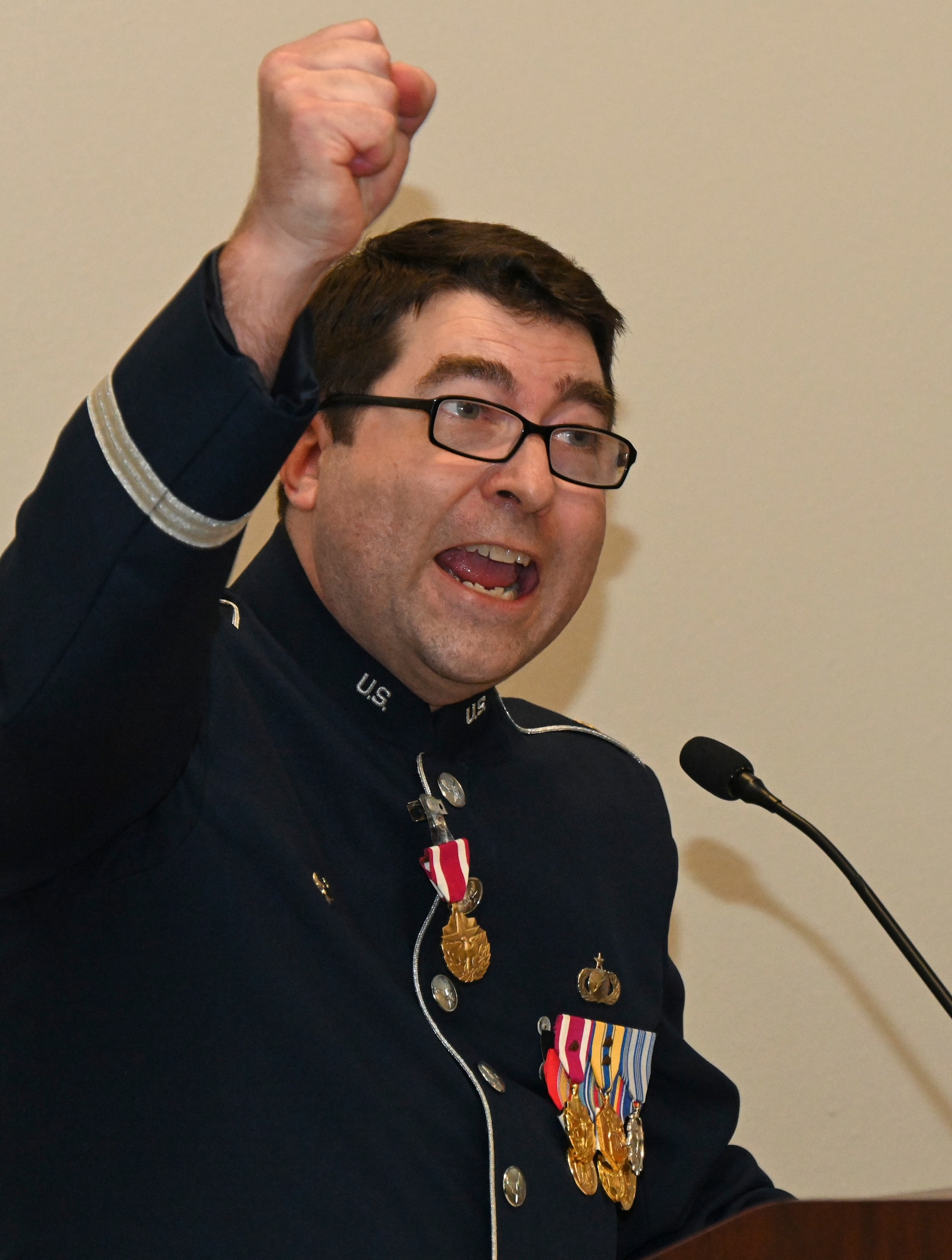 Air Force officer in a band uniform raises his hand in the air.