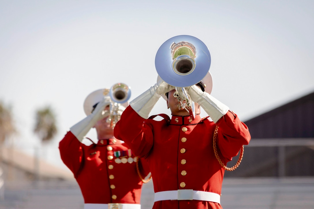 Two Marines dressed in ceremonial uniforms play instruments.