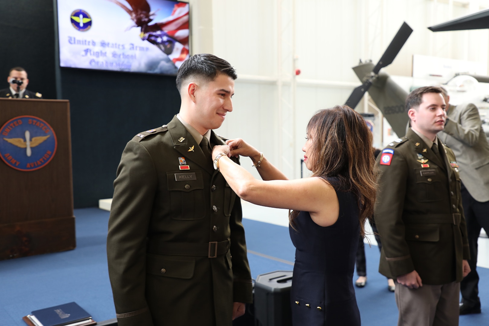 Warrant Officer Paul D. Kelly's mother, Maria, pins his silver wings on his uniform as he graduates flight school as a Black Hawk pilot at Fort Novosel, Ala., Feb. 8, 2024. He serves with the Virginia Army National Guard.
