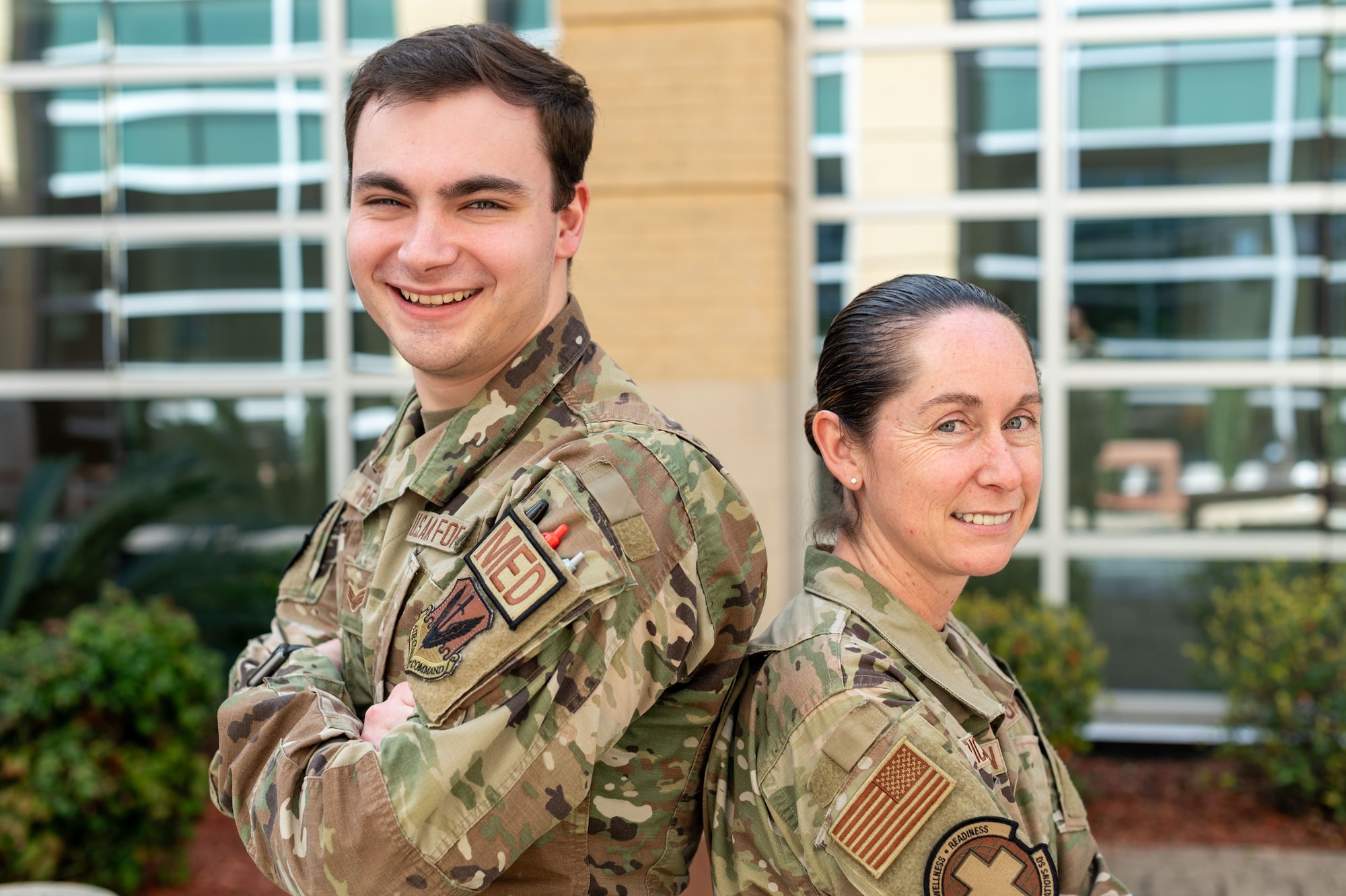 Two Airmen standing back to back.