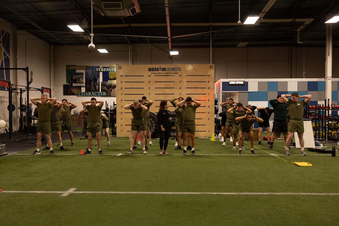 U.S. Marines attending an Expeditionary Communications Course with the Marine Corps Communication Electronics School, stretch for a cognitive strength and conditioning test at Wilburn gym, Marine Corps Air-Ground Combat Center, Twentynine Palms, California, March 4, 2024. ECC trains Marines in expeditionary skillsets that enable them to operate independently and to assemble various types of communication equipment in any environment across the full range of military operations. (U.S. Marine Corps photo by Lance Cpl. Anna Higman)