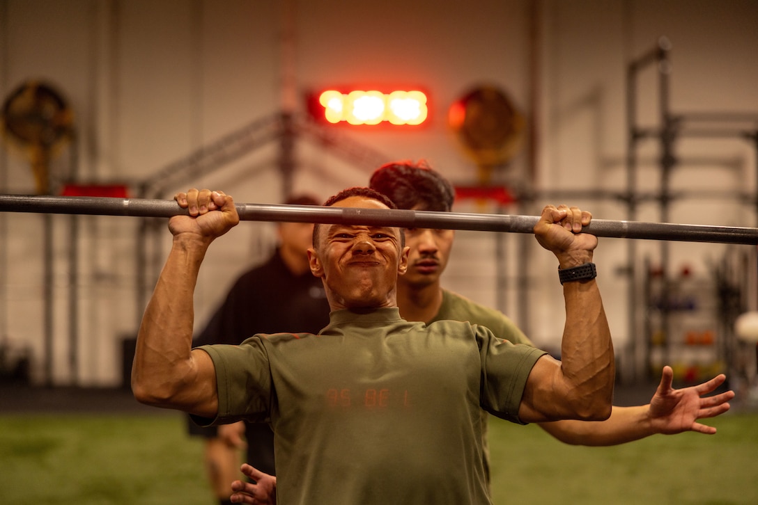 U.S. Marine Corps Lance Cpl. Desmond Kanelos, an Oceanside, California native, transmission system operator with Headquarters Battalion, 12th Marine Littoral Regiment, 3rd Marine Division, lifts weights for a cognitive strength and conditioning test during an Expeditionary Communications Course with the Marine Corps Communication Electronics School at Wilburn gym, Marine Corps Air-Ground Combat Center, Twentynine Palms, California, March 4, 2024. ECC trains Marines in expeditionary skillsets that enable them to operate independently and to assemble various types of communication equipment in any environment across the full range of military operations. (U.S. Marine Corps photo by Lance Cpl. Anna Higman)