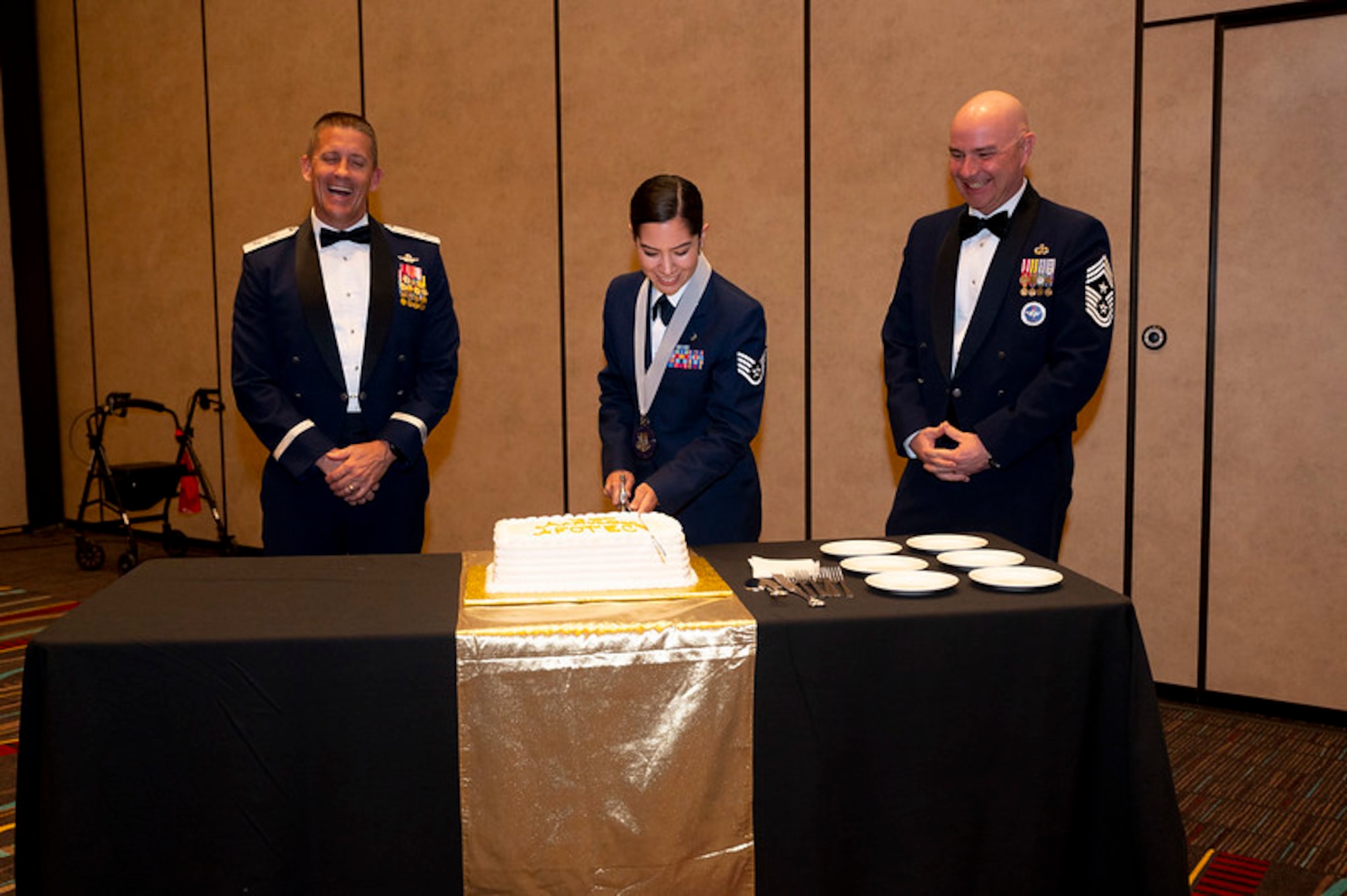 SSgt. Abrielle Maes (Center) cuts the cake for the Air Force Operational Test and Evaluation Center 50th Anniversary Celebration with the AFOTEC Commander Maj. Gen. Trey Rawls (left) and AFOTEC Command Chief CMSgt. John Burgess (right). Tradition is for the youngest member of an organization to cut the ceremonial cake.