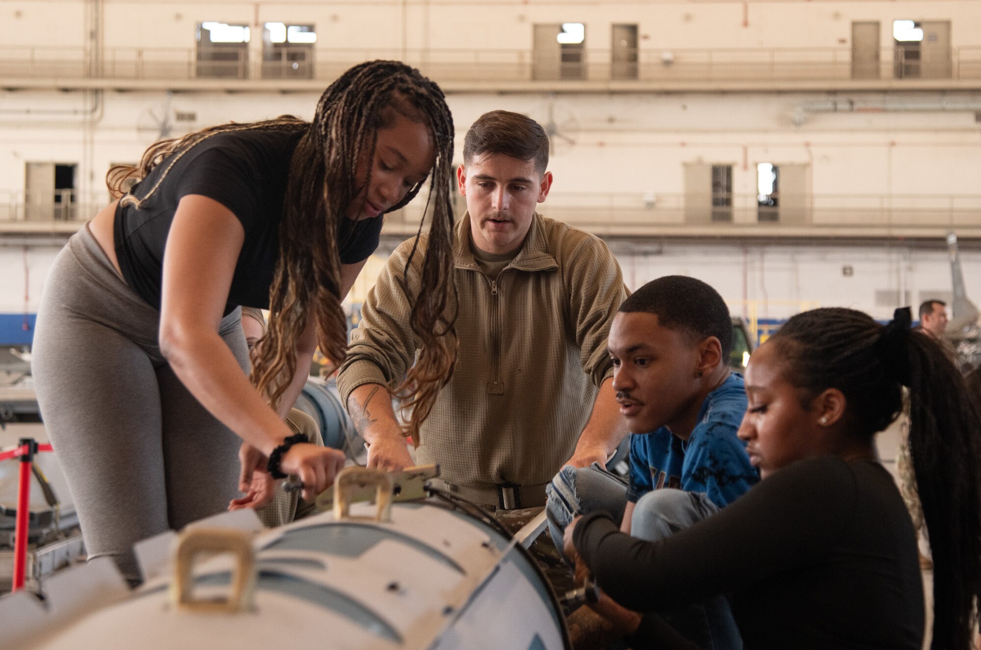 An Airman guides a group of volunteers during a weapons load demonstration.