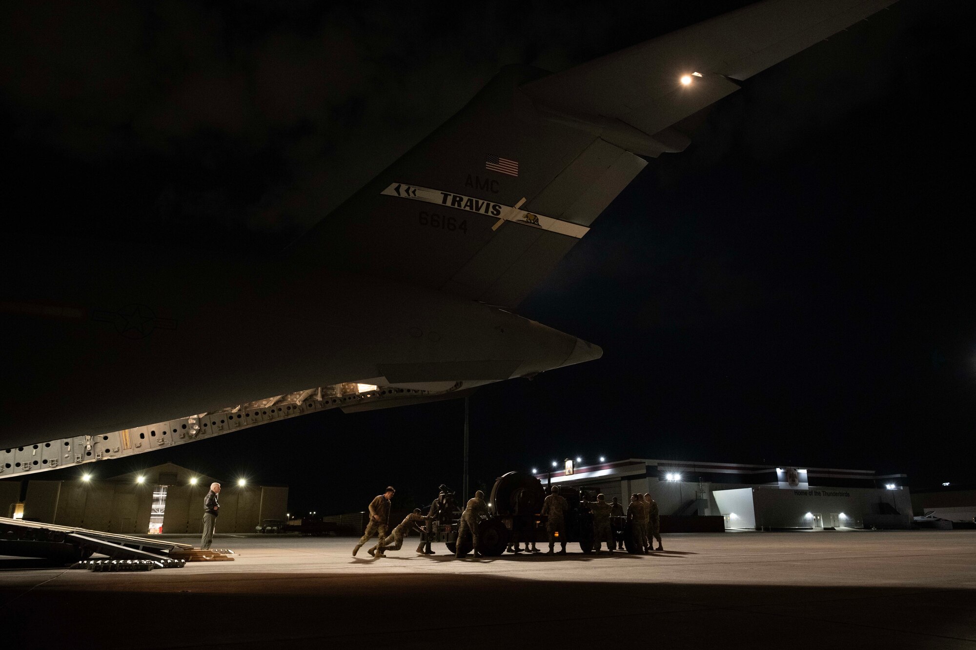 Airmen push machinery onto a large military aircraft.