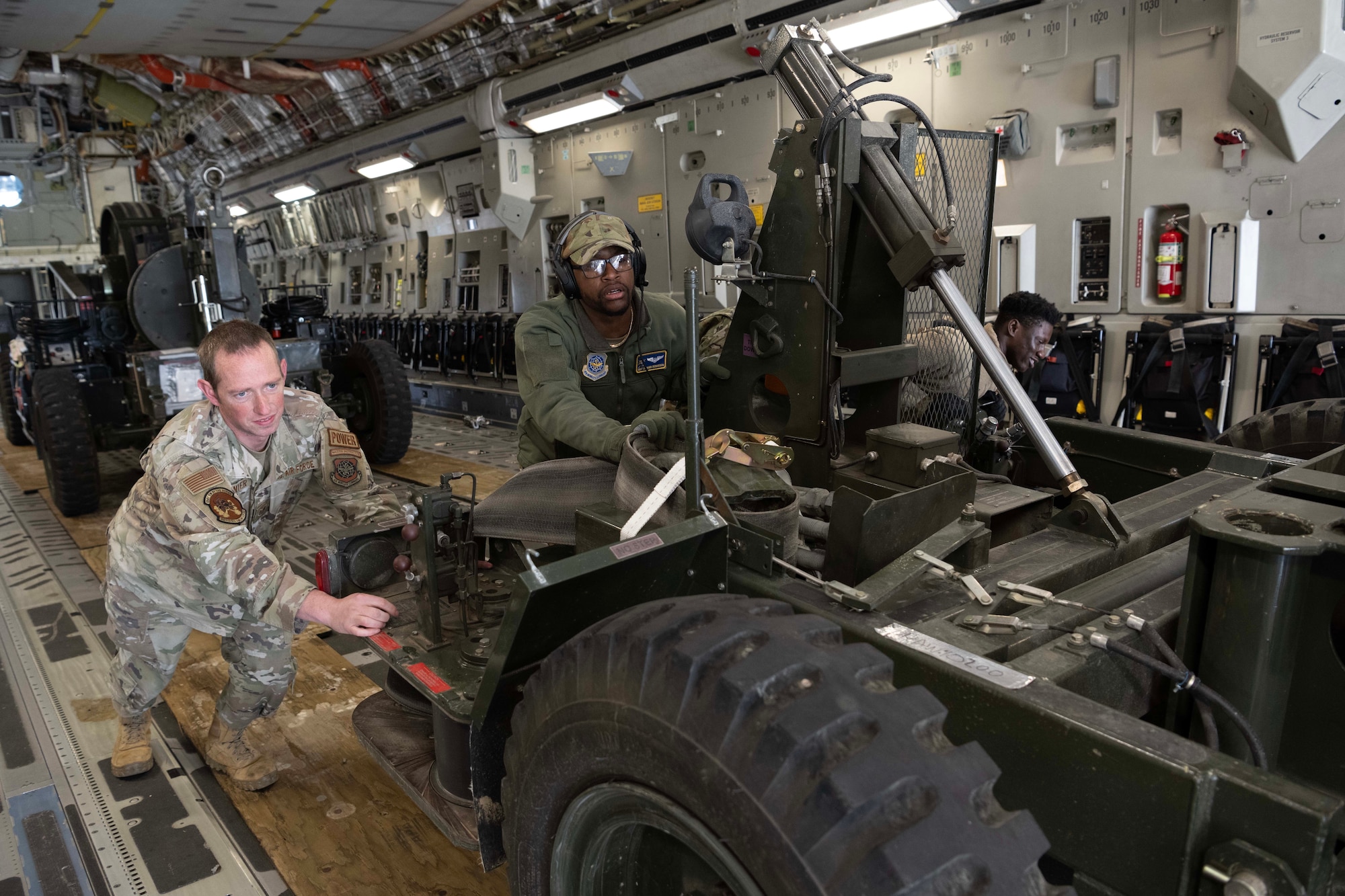 Airmen push machinery off of a large military aircraft