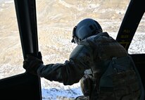 Flight engineer leans out the door of a hovering UH-1N