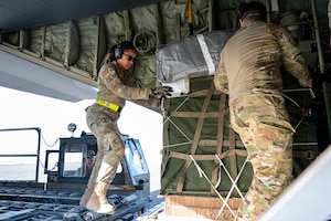 Loadmasters inspect humanitarian aid loaded aboard a C-130 at an undisclosed location.
