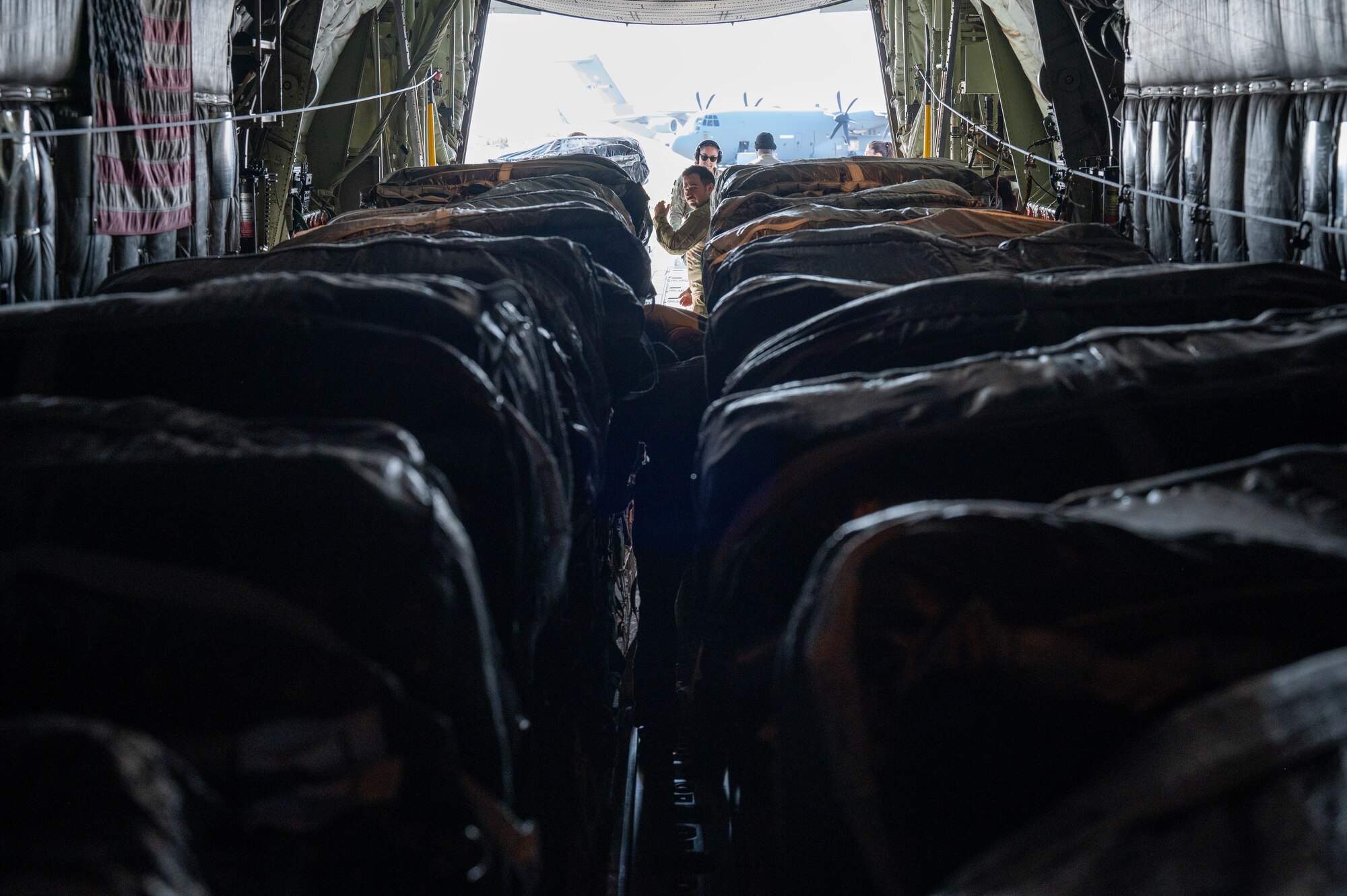 Loadmasters inspect humanitarian aid loaded aboard a C-130at an undisclosed location.