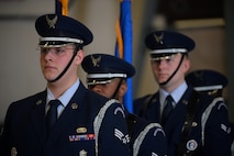Four men in dark blue ceremonial military uniform stand in a line facing the left.