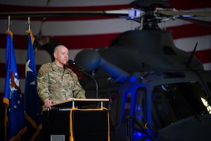 Man in military uniform stands behind podium to speak into a microphone.