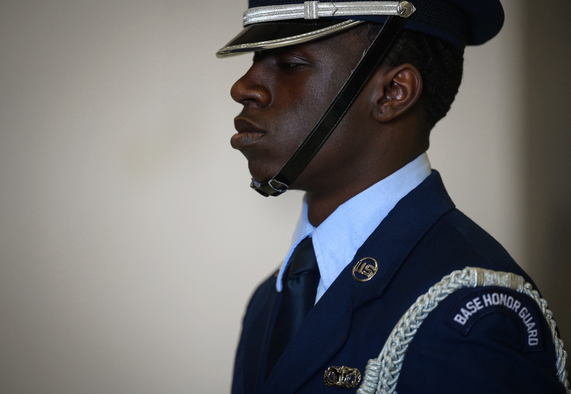 Side profile of a man in dark blue ceremonial military uniform and black cap with chin strap.