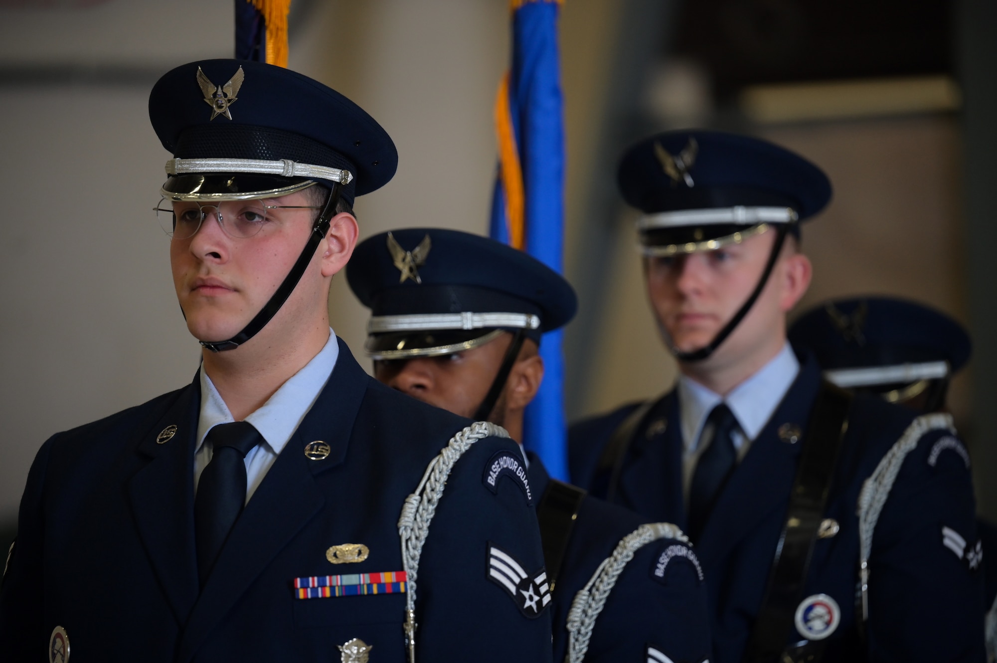 Four men in dark blue ceremonial military uniform stand in a line facing the left.