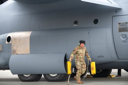 U.S. Air Force Senior Airman Giovanni Elias, 374th Aircraft Maintenance Squadron flight crew chief, removes the chocks from a C-130J Super Hercules.