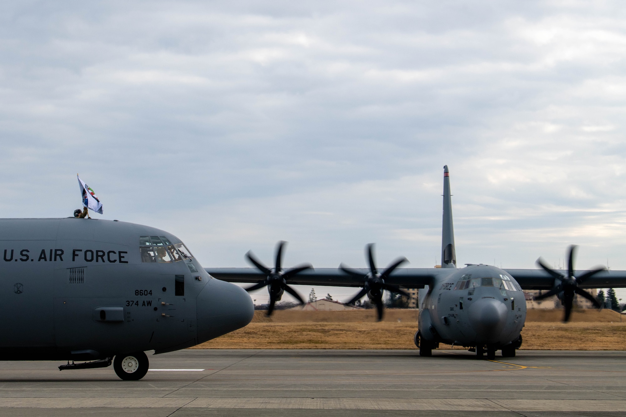 An Airman assigned to the 36th Airlift Squadron waves a flag from a C-130J Super Hercules.