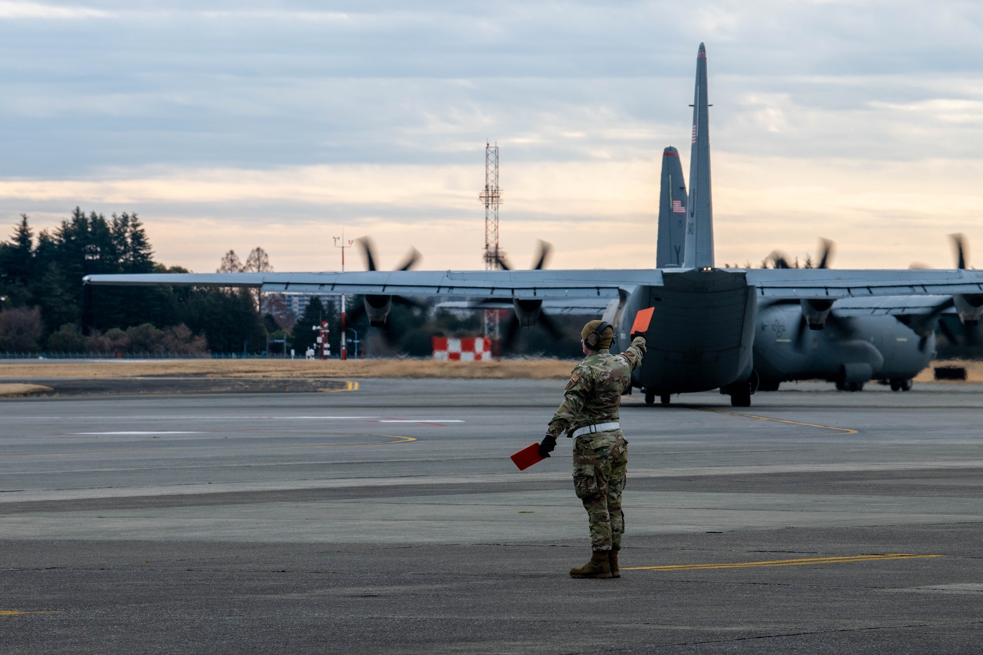 A member of the 374th Aircraft Maintenance Squadron (AMXS) marshals a C-130J Super Hercules.