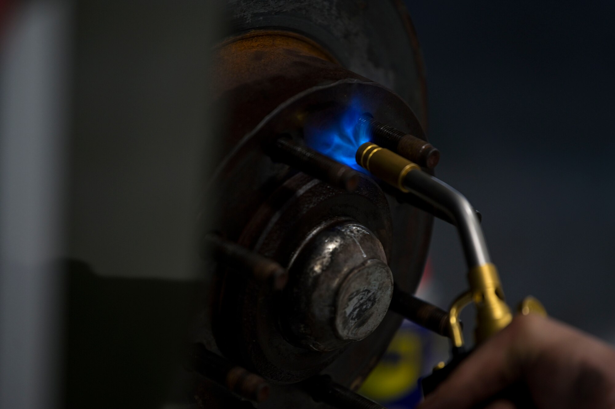 U.S. Air Force Airman 1st Class Misael Iasalle, a 1st Special Operations Logistics Readiness Squadron vehicle maintenance journeyman, heats a rim with a torch.
