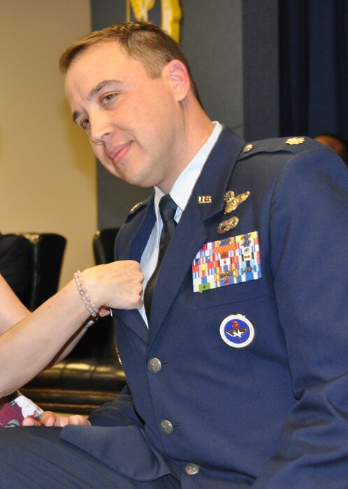 a man has his family pin a button to his uniform