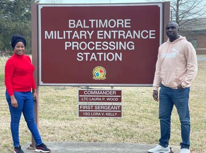Man and women pose with the Baltimore Military Entrance Processing Station sign.