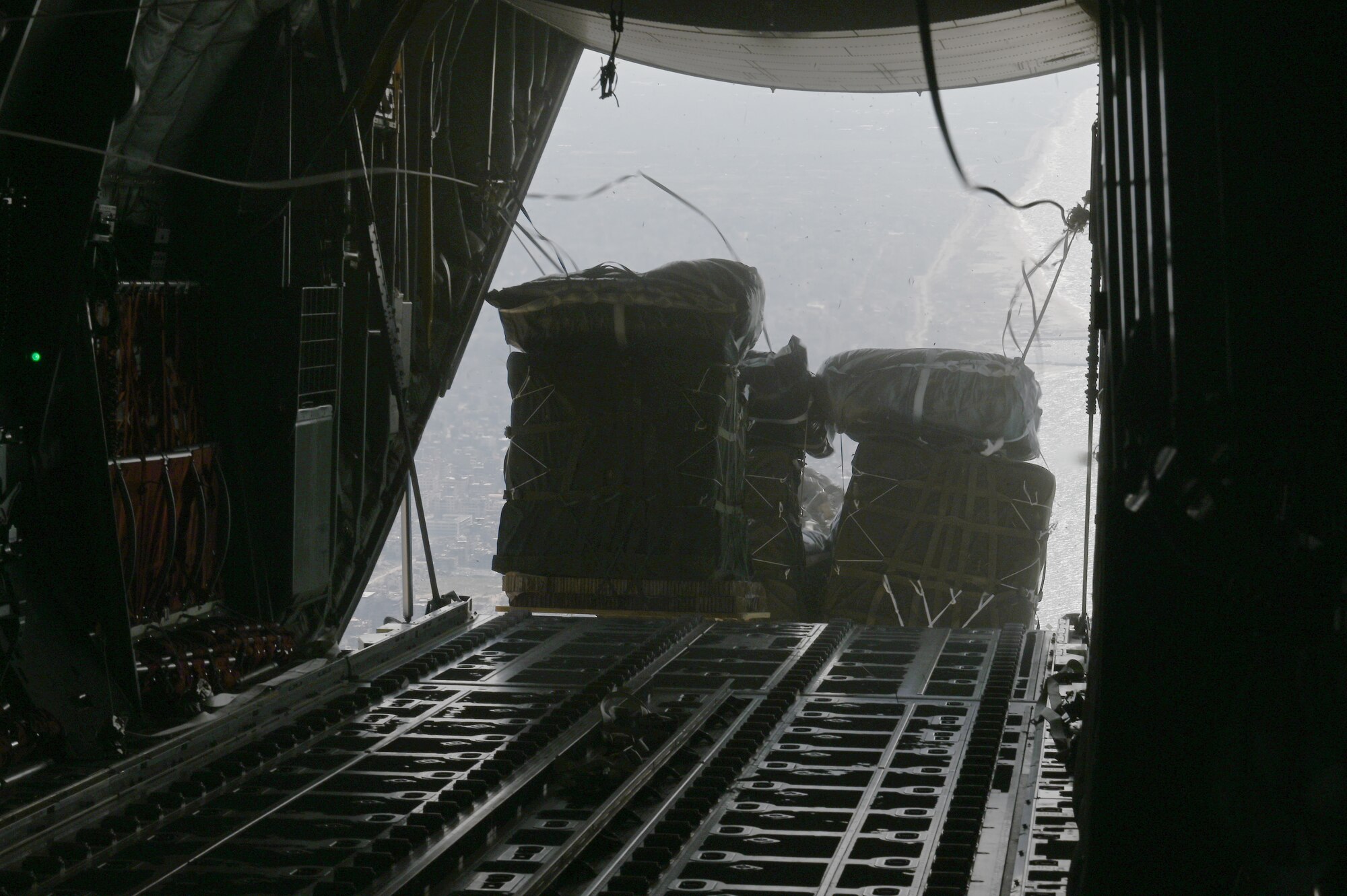 An HC-130J airdrops pallets of food and water over Gaza.