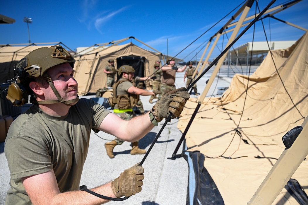 Tech. Sgt. Michael Washburn, left, 433rd Contingency Response Flight non-commissioned officer, fastens tent ropes at a training campsite during a training event at Joint Base San Antonio-Lackland, Texas on Mar. 2, 2024.