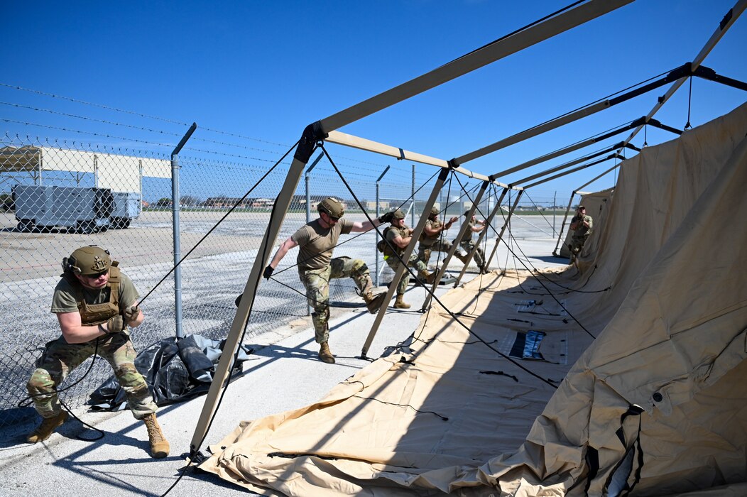 Members of the 433rd Contingency Response Flight work to together to hoist up a tent at a training campsite during a training event at Joint Base San Antonio-Lackland, Texas on Mar. 2, 2024.