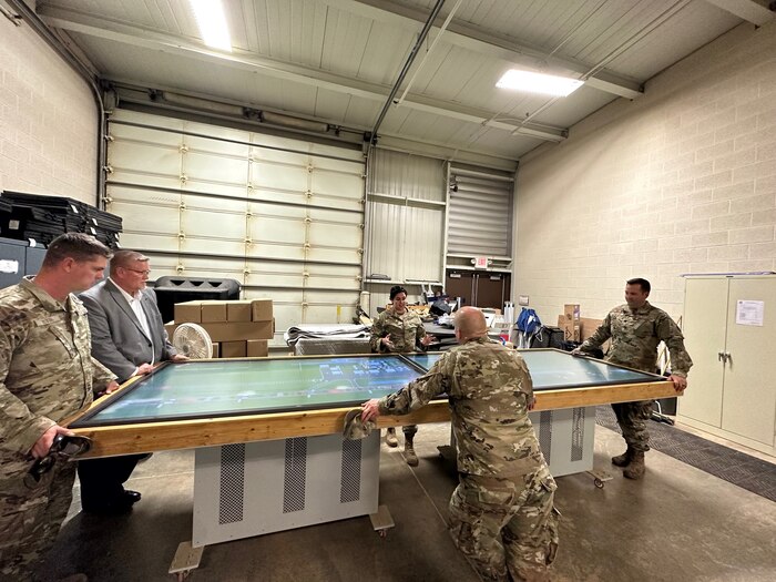 Airmen stand around table for presentation