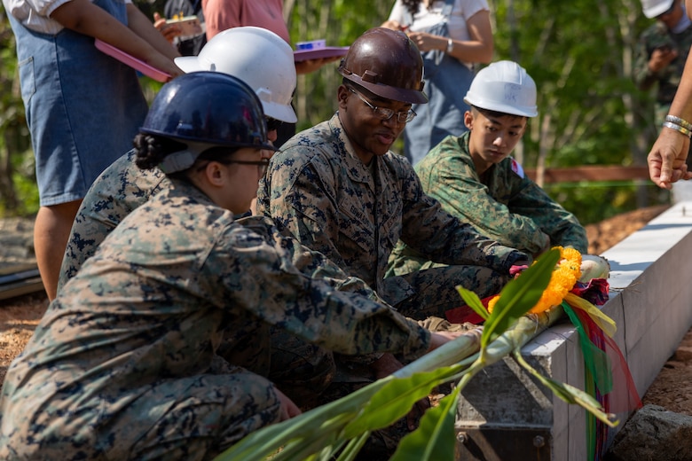 U.S. Marines with Marine Wing Support Squadron (MWSS) 171, Marine Aircraft Group 12, and a member of the Singapore Army with the 30th Combat Engineer Brigade kneels down by a pillar during a blessing ceremony at the Ban Prakaet school in Chanthaburi, Thailand, Feb. 11, 2024. Marines of MWSS-171 lent their engineering expertise to multilateral humanitarian efforts during Cobra Gold 24. Joint Exercise Cobra Gold is the largest joint exercise in mainland Asia and a concrete example of the strong alliance and strategic relationship between Thailand and the United States. This year will be the 43rd iteration of the multilateral exercise and will be held from Feb. 27 to March 8, 2024. (U.S. Marine Corps photo by Cpl. Calah Thompson)